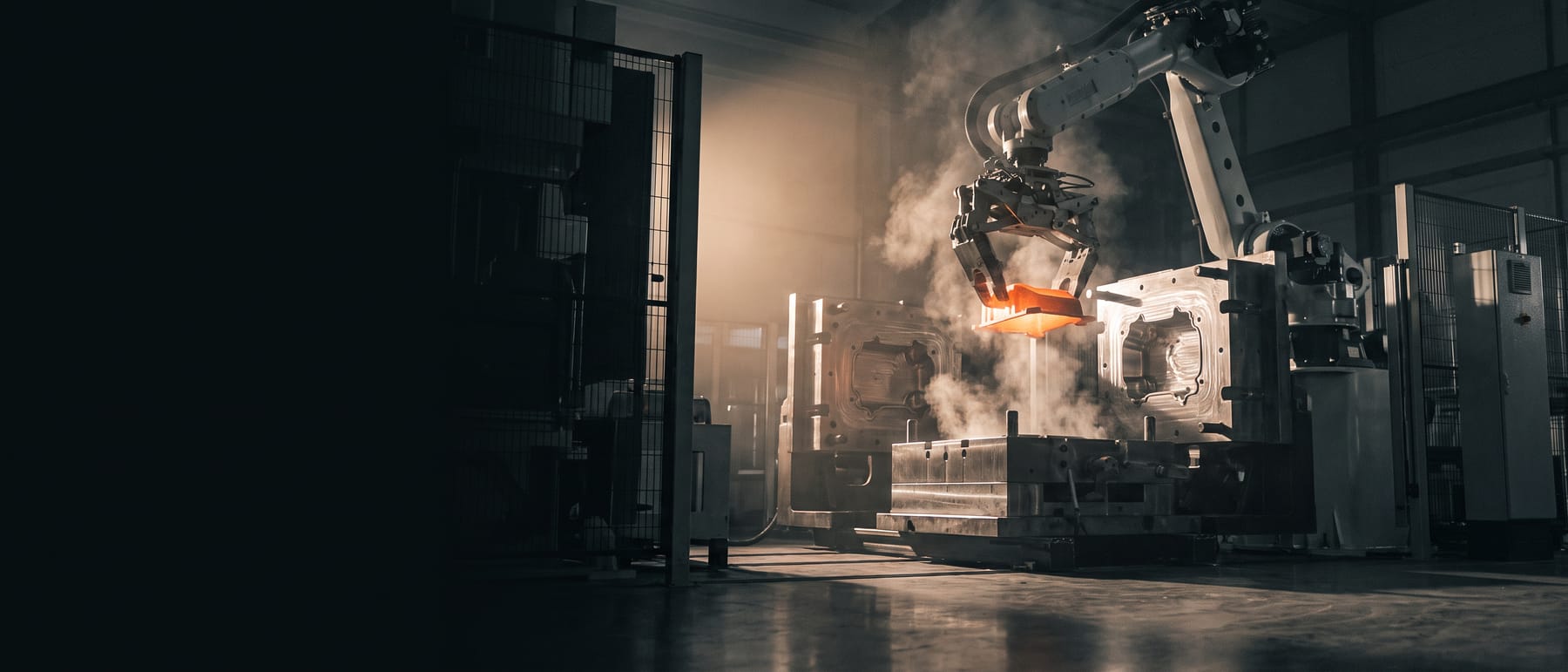 Robotarm lyfter en glödande, nygjuten aluminiumdetalj ur ett pressgjutverktyg.
